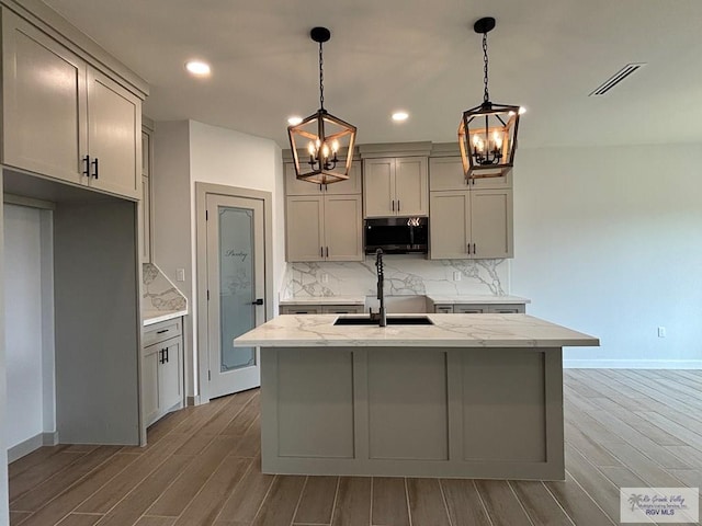 kitchen with stainless steel microwave, a sink, a notable chandelier, and visible vents