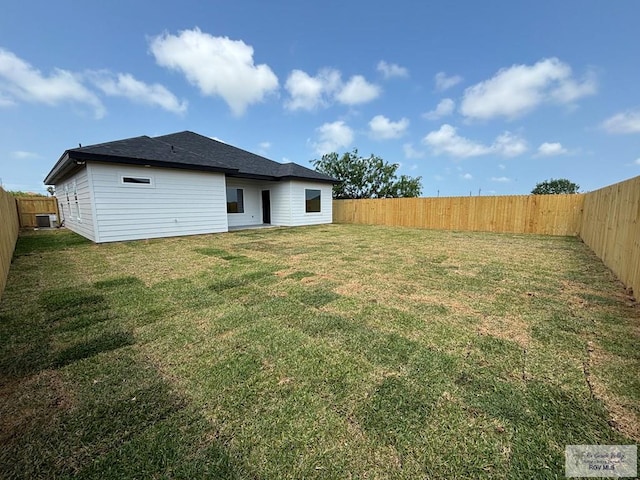 back of house with a yard and a fenced backyard