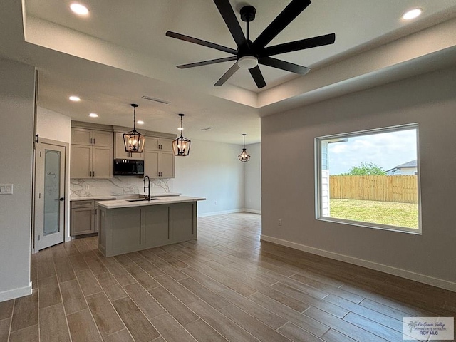 kitchen with black microwave, light countertops, a tray ceiling, baseboards, and recessed lighting