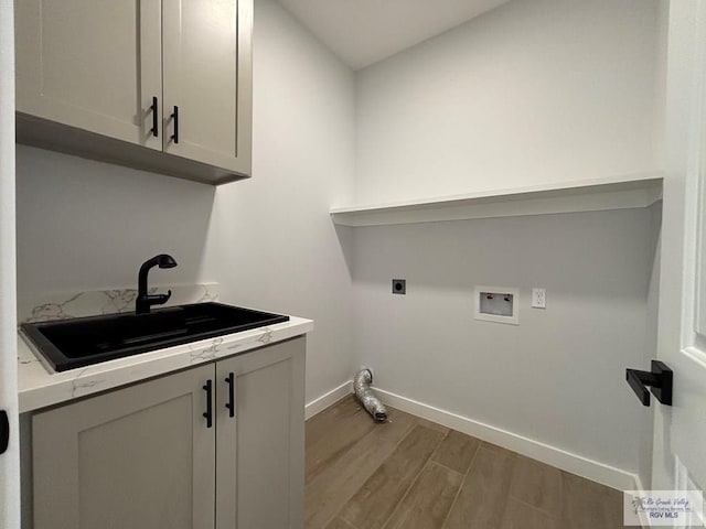 laundry area featuring wood finished floors, cabinet space, hookup for an electric dryer, a sink, and baseboards