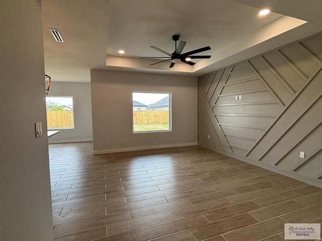 spare room with wood tiled floor, a raised ceiling, ceiling fan, and visible vents