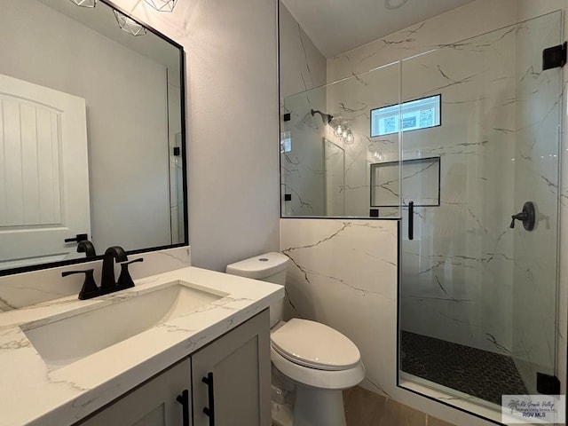 full bath featuring toilet, a marble finish shower, and vanity