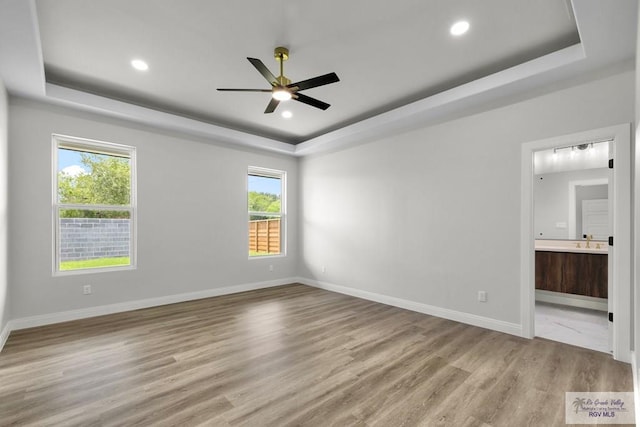 1013 Butler St, Edinburg, TX 78541 - unfurnished bedroom featuring a raised ceiling, light wood finished floors, baseboards, ensuite bathroom, and recessed lighting
