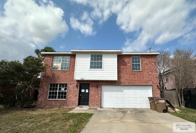 traditional home with brick siding, a front yard, fence, a garage, and driveway