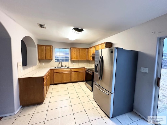 kitchen with stainless steel appliances, tasteful backsplash, light countertops, visible vents, and a sink