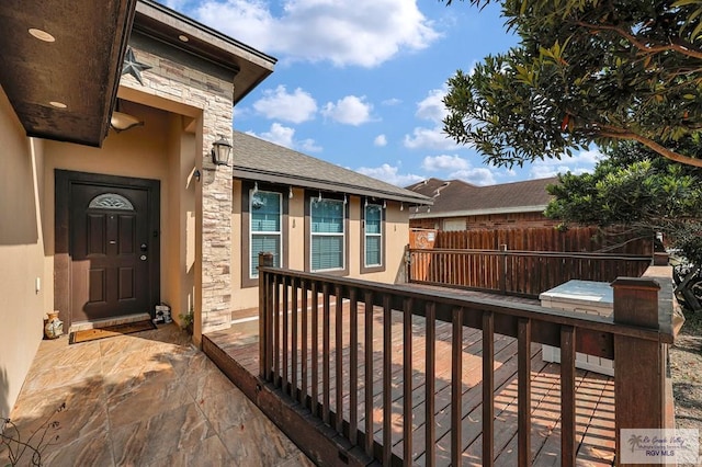 exterior space with stucco siding, fence, and stone siding