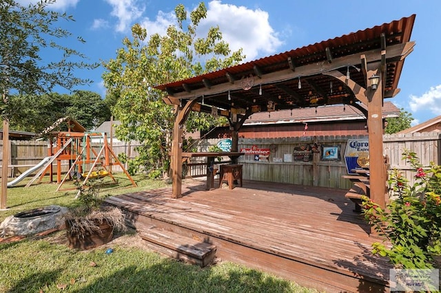 deck with a fenced backyard, a yard, and a playground