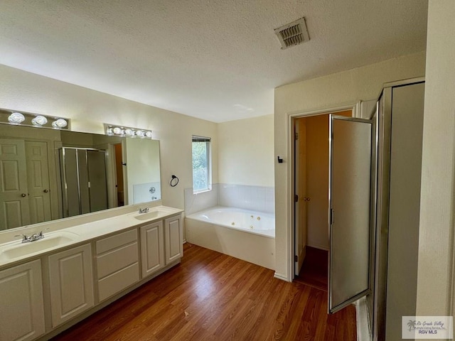 2100 Emory Ave Unit 291, Mcallen, TX 78504 - full bathroom with a shower stall, a textured ceiling, wood finished floors, a jetted tub, and double vanity
