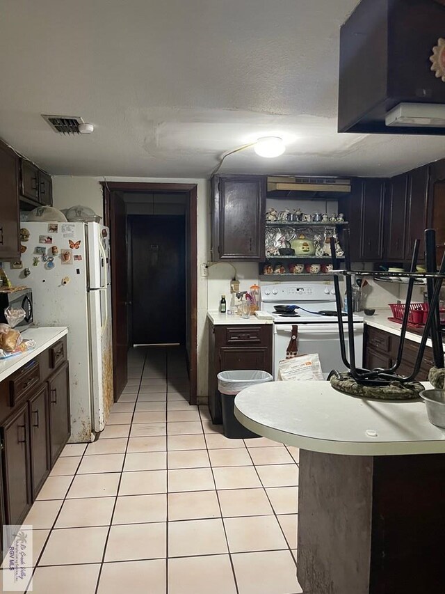 103 Alan A Dale St, Brownsville, TX 78521 - kitchen featuring white appliances, light countertops, light tile patterned floors, and dark brown cabinetry