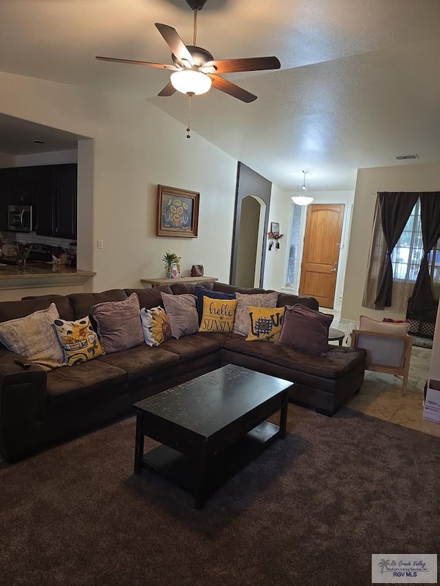 living area featuring lofted ceiling, visible vents, ceiling fan, carpet floors, and arched walkways