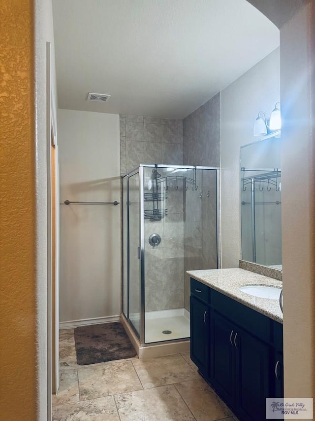 full bath with stone finish flooring, vanity, a shower stall, and visible vents