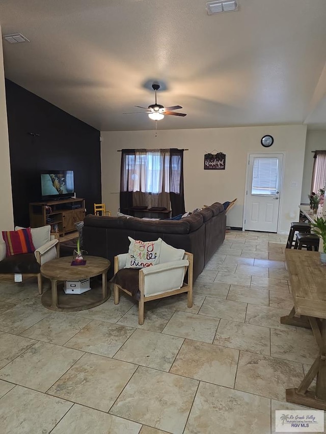 living room featuring ceiling fan, stone finish floor, and visible vents