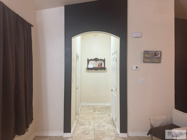 corridor featuring baseboards and arched walkways
