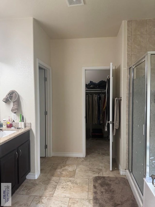 bathroom featuring vanity, visible vents, a stall shower, and a spacious closet