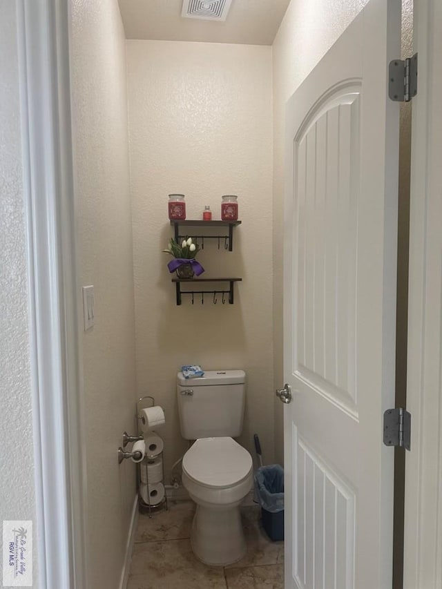bathroom featuring toilet, baseboards, visible vents, and tile patterned floors