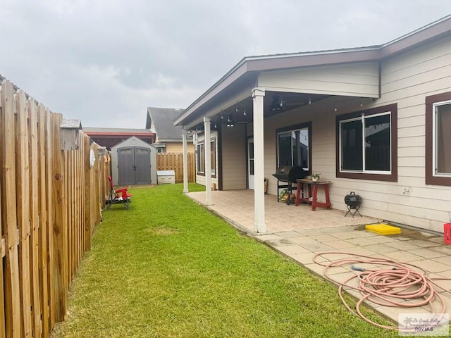 rear view of house featuring a storage shed, an outdoor structure, a patio area, a fenced backyard, and a lawn