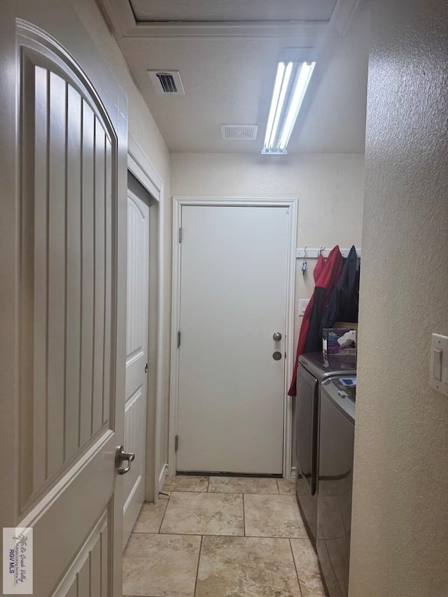 clothes washing area featuring washing machine and clothes dryer, a textured wall, visible vents, and laundry area