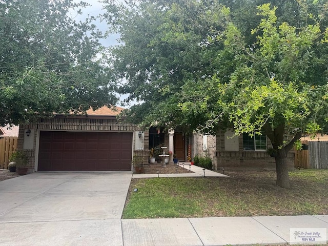 obstructed view of property featuring brick siding, driveway, fence, and a garage