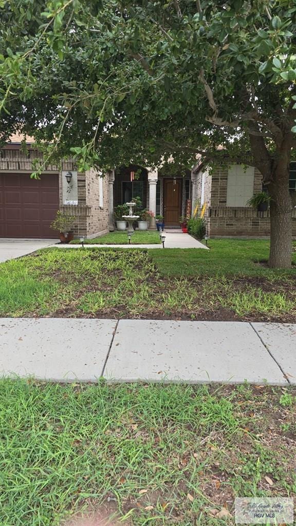 3564 Oviedo Dr, Brownsville, TX 78520 - view of property hidden behind natural elements with brick siding, a garage, and a front lawn
