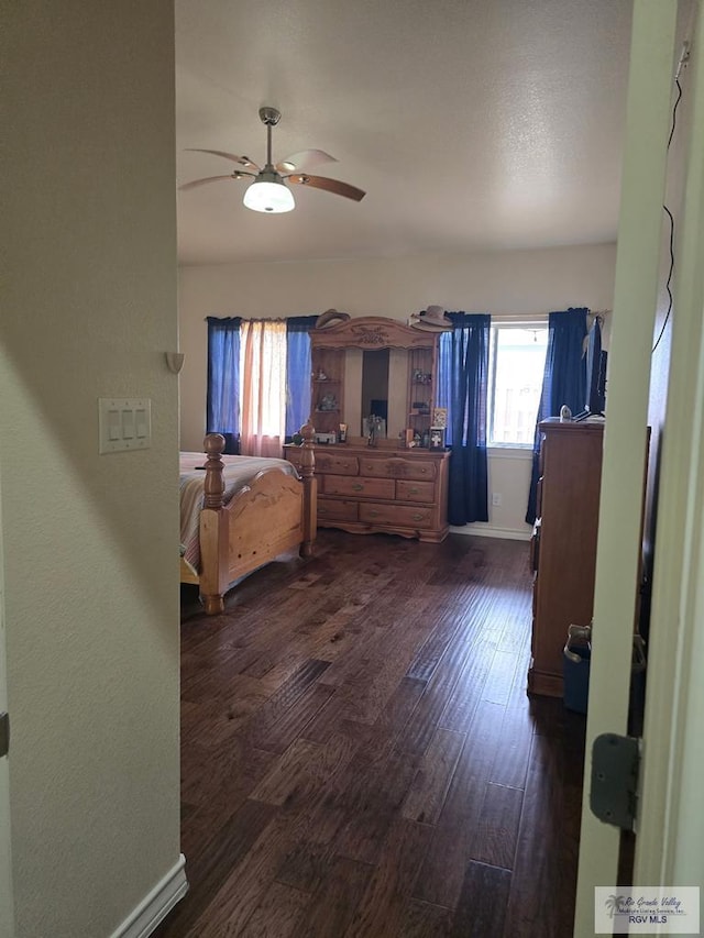 bedroom featuring baseboards, ceiling fan, and dark wood-style floors