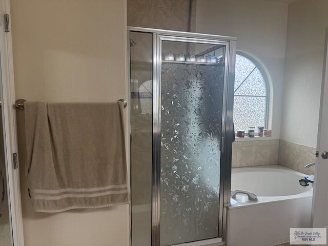 bathroom with a stall shower and a garden tub