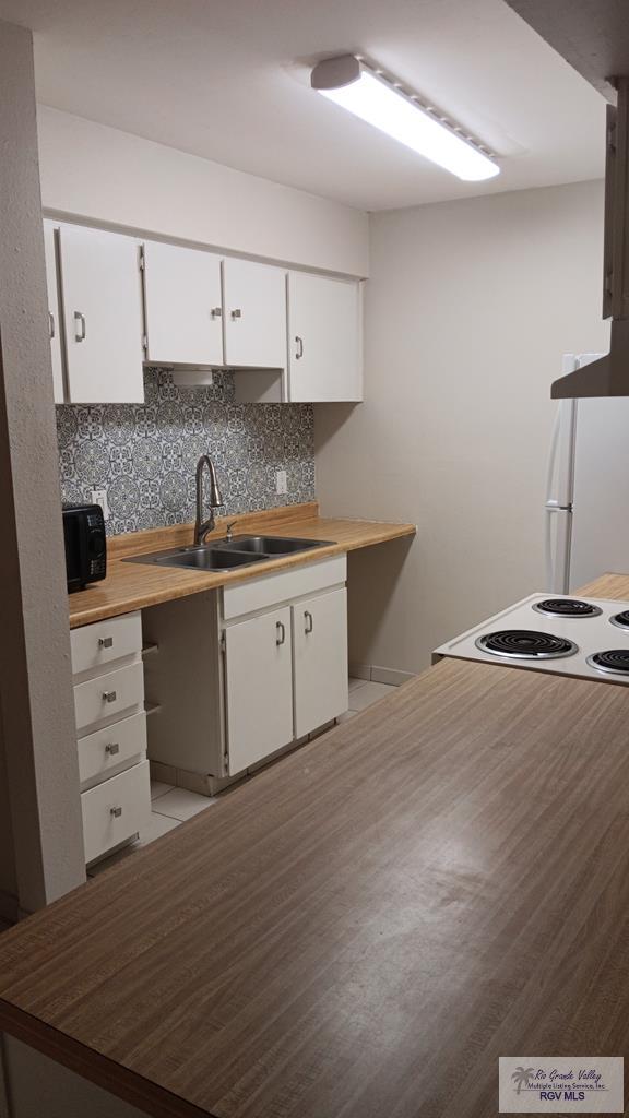 2 Palmetto Ct, Brownsville, TX 78521 - kitchen featuring white cabinetry, tasteful backsplash, electric stove, and wall chimney exhaust hood