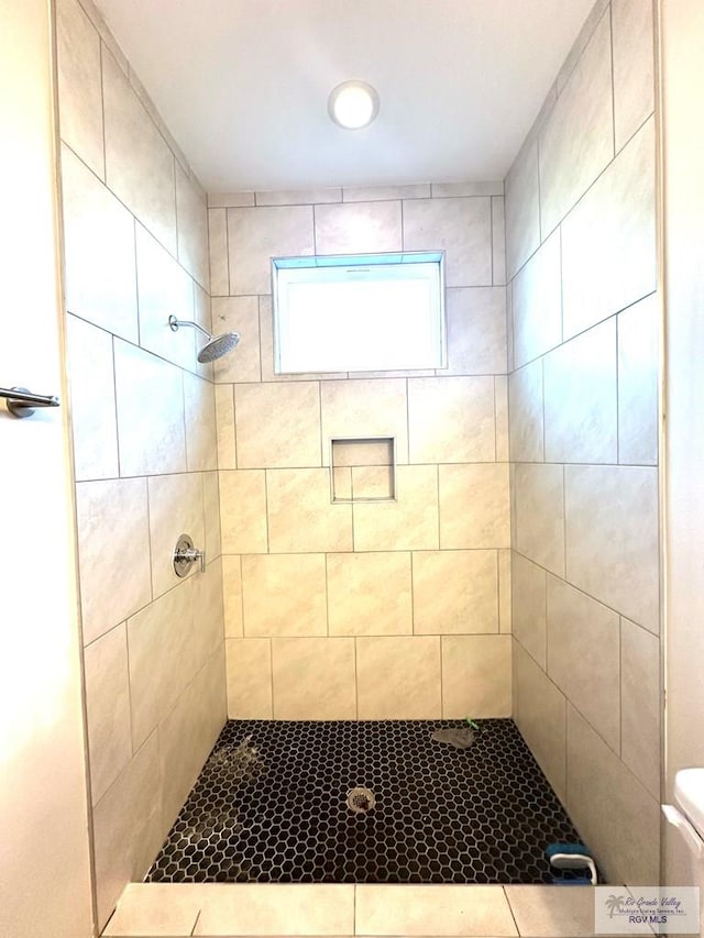 bathroom featuring toilet and a tile shower