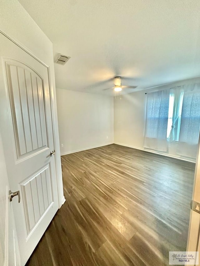 unfurnished room with dark wood-type flooring and ceiling fan