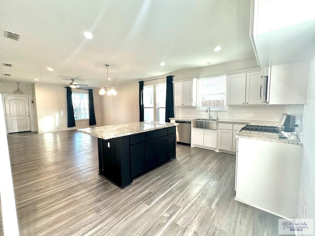 kitchen featuring tasteful backsplash, stainless steel appliances, white cabinets, pendant lighting, and a kitchen island