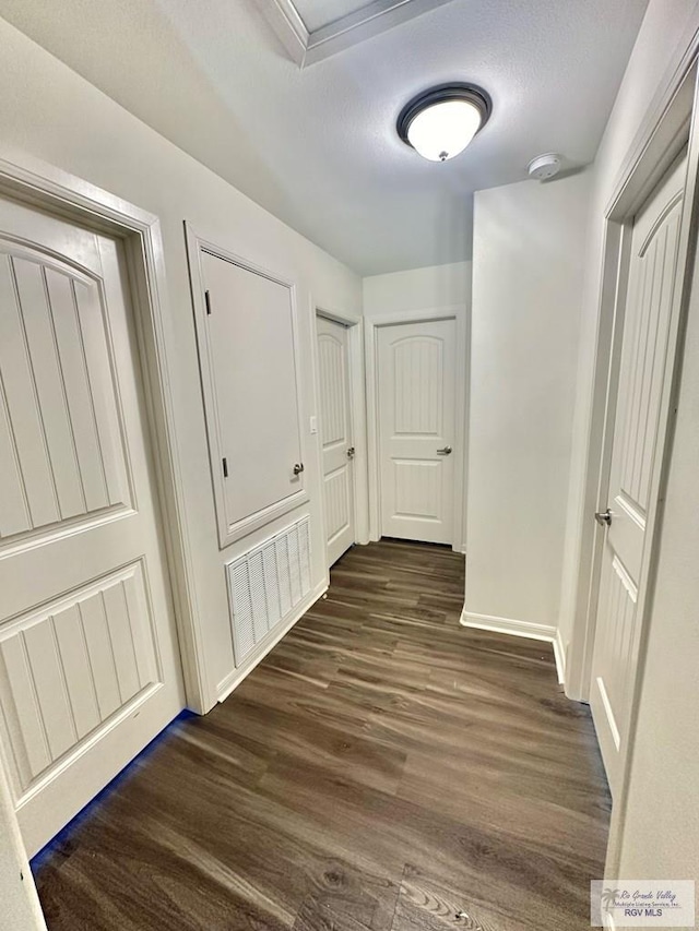 hall featuring dark wood-type flooring and a textured ceiling