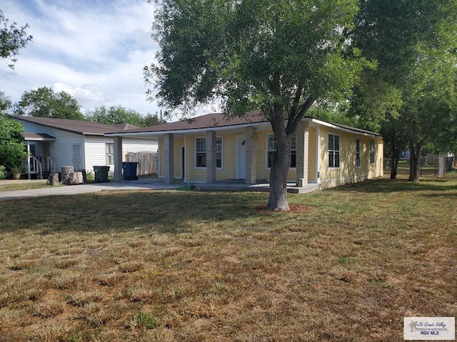 view of front of property with an attached carport, a front yard, and fence