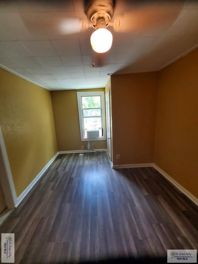 spare room with baseboards and dark wood-style flooring