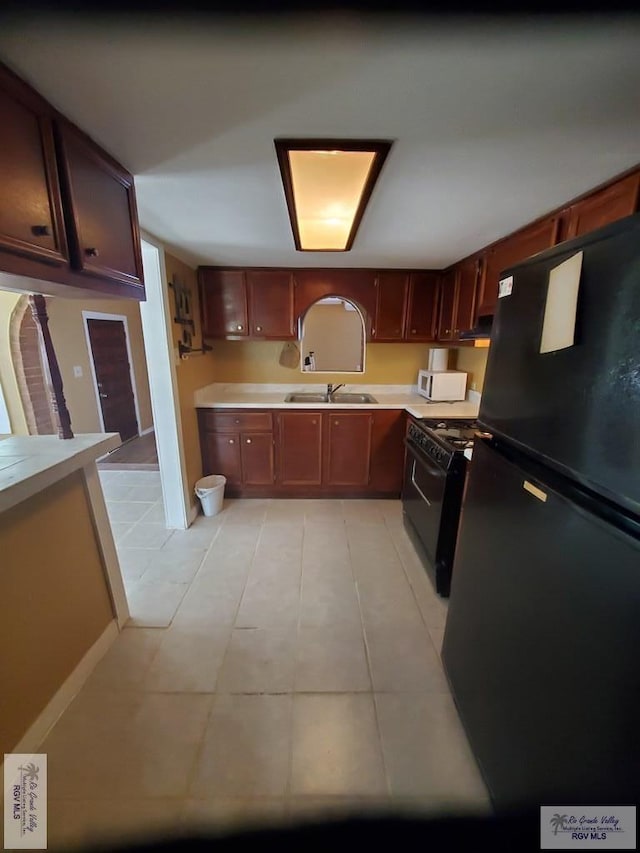 kitchen featuring a sink, black appliances, light tile patterned floors, and light countertops