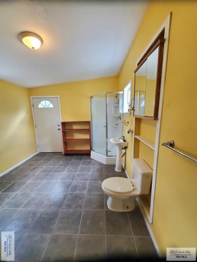 bathroom with tile patterned floors, a stall shower, toilet, and baseboards