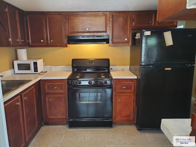 kitchen featuring light tile patterned floors, a sink, black appliances, light countertops, and under cabinet range hood