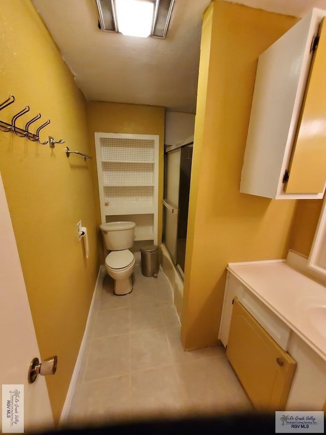 bathroom with an enclosed shower, toilet, vanity, and tile patterned flooring