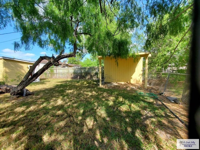 view of yard with an outdoor structure, fence, and a shed