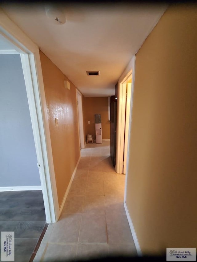 hallway featuring light tile patterned flooring, baseboards, and visible vents