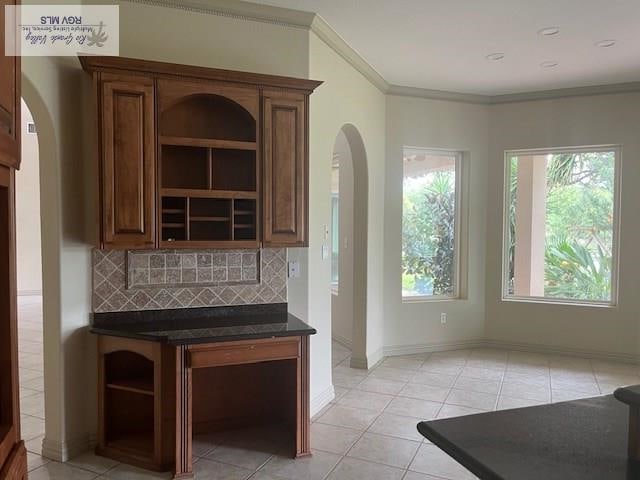 71 Cortez Ave, Rancho Viejo, TX 78575 - kitchen featuring open shelves, arched walkways, tasteful backsplash, dark countertops, and light tile patterned floors