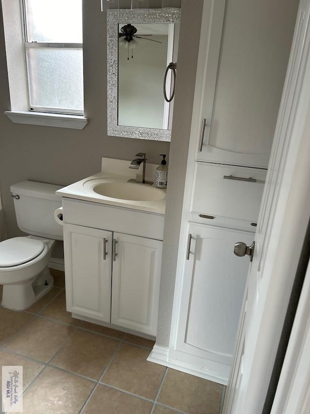 bathroom with baseboards, toilet, ceiling fan, tile patterned floors, and vanity