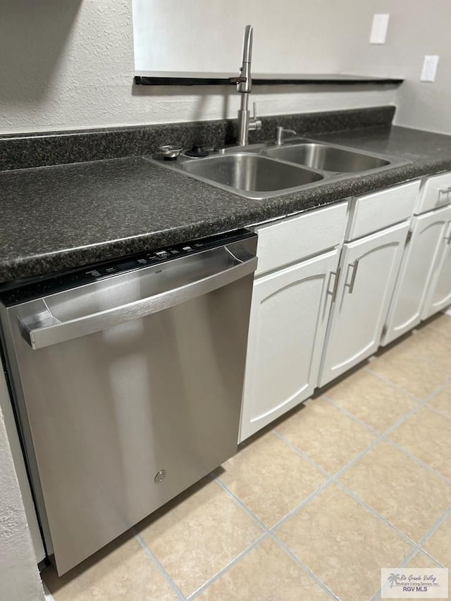 kitchen featuring light tile patterned flooring, a sink, white cabinets, dishwasher, and dark countertops