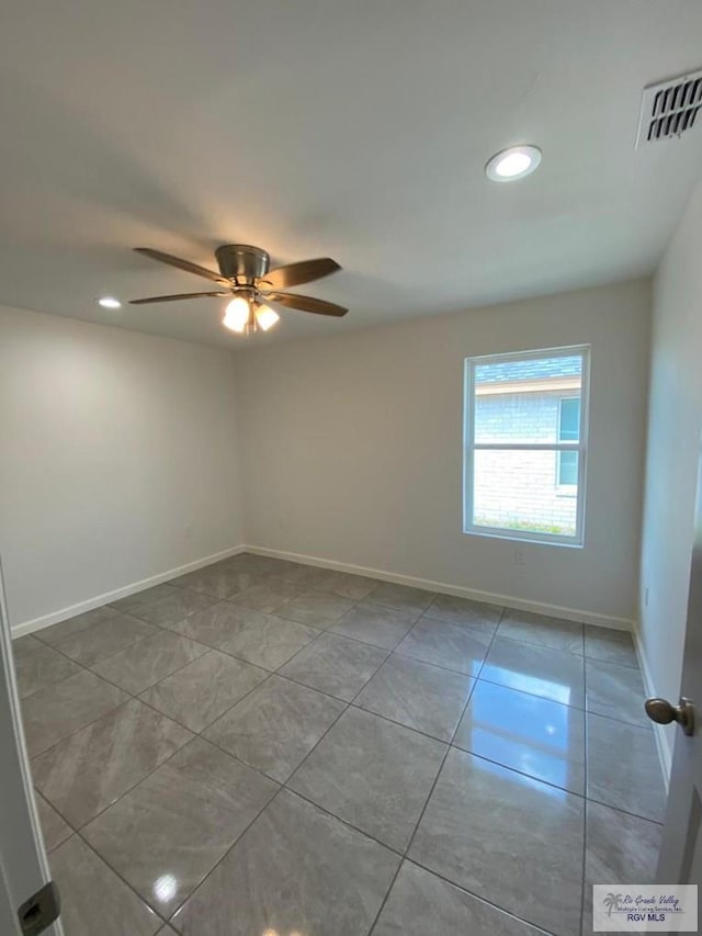 spare room with ceiling fan and light tile patterned floors