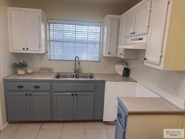 kitchen featuring backsplash, sink, gray cabinets, white cabinetry, and light tile patterned flooring