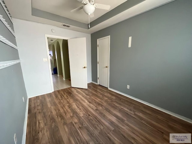 empty room featuring a tray ceiling, ceiling fan, and hardwood / wood-style flooring