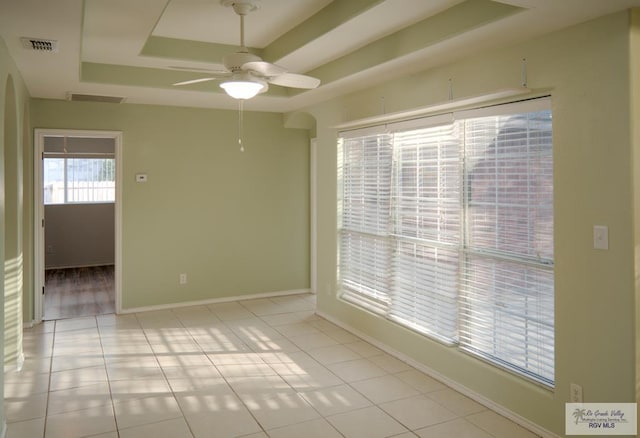 tiled spare room with a raised ceiling and ceiling fan