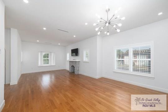 unfurnished living room with a notable chandelier and light wood-type flooring