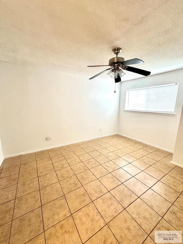 spare room with ceiling fan, light tile patterned flooring, and a textured ceiling