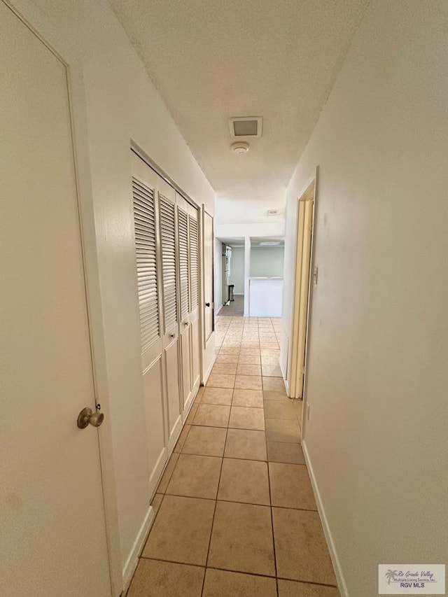 corridor featuring light tile patterned floors and a textured ceiling