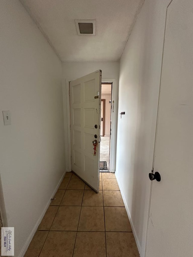 corridor featuring tile patterned flooring and a textured ceiling