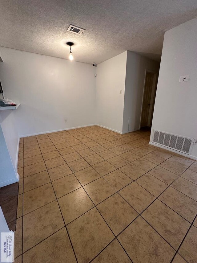 unfurnished room featuring light tile patterned floors and a textured ceiling